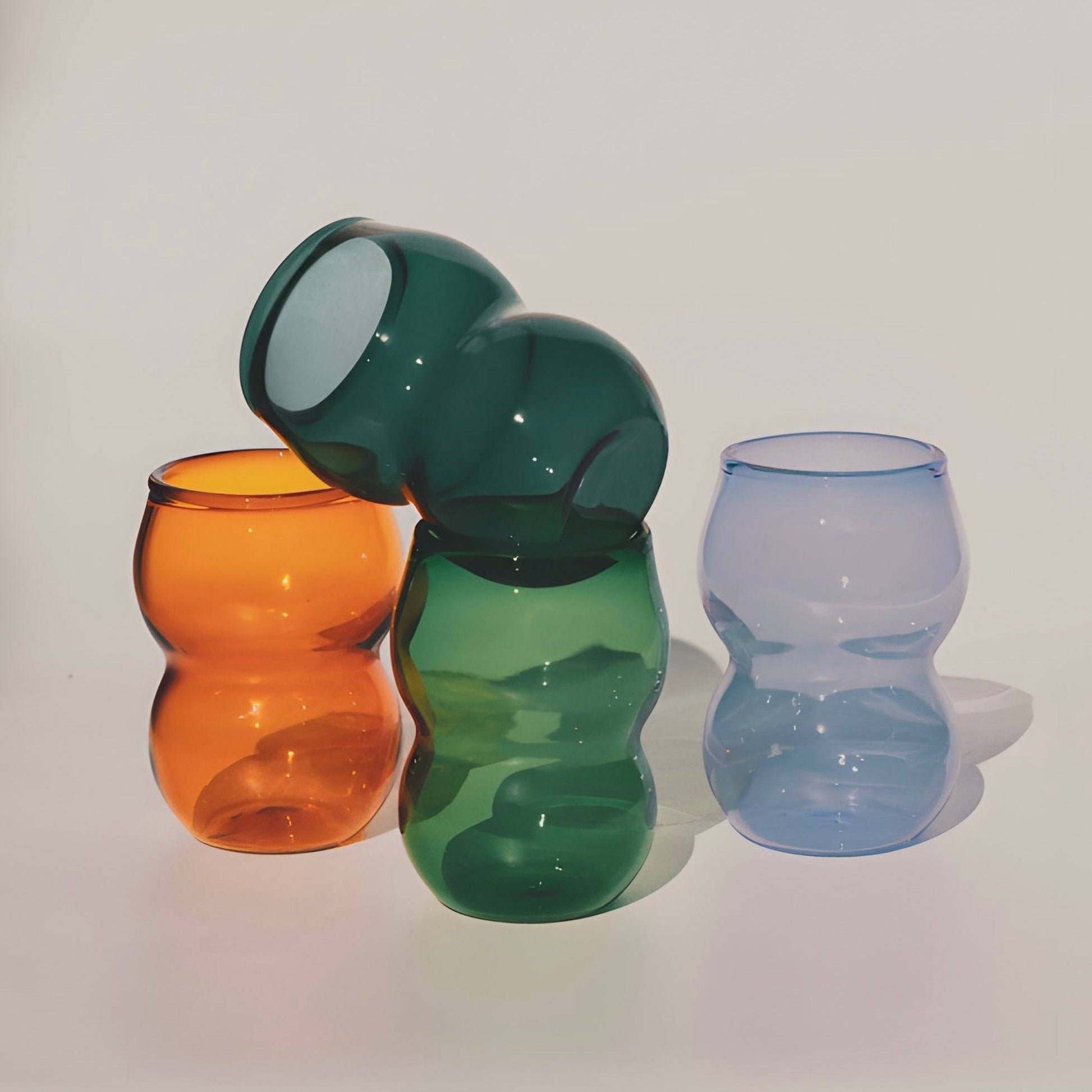 Dreamlike up Quartet cups in curvy, elegant form featuring vibrant orange, green, and translucent blue hues. Perfect for modern tableware.