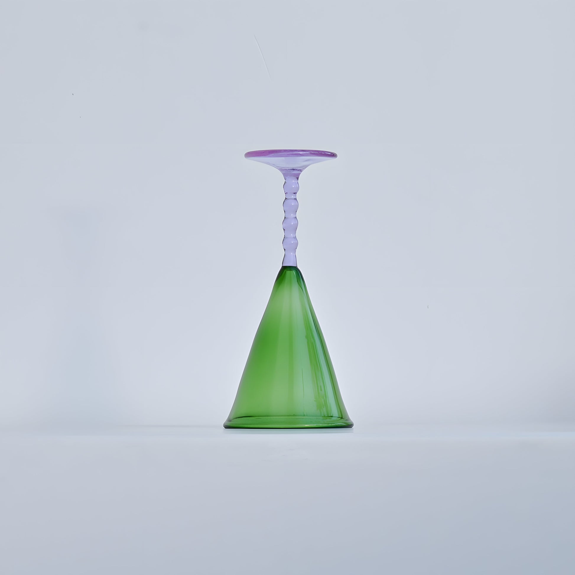 A single Teta Edit Liquor glass in green and lavender, placed upside down to highlight its unique handcrafted design.