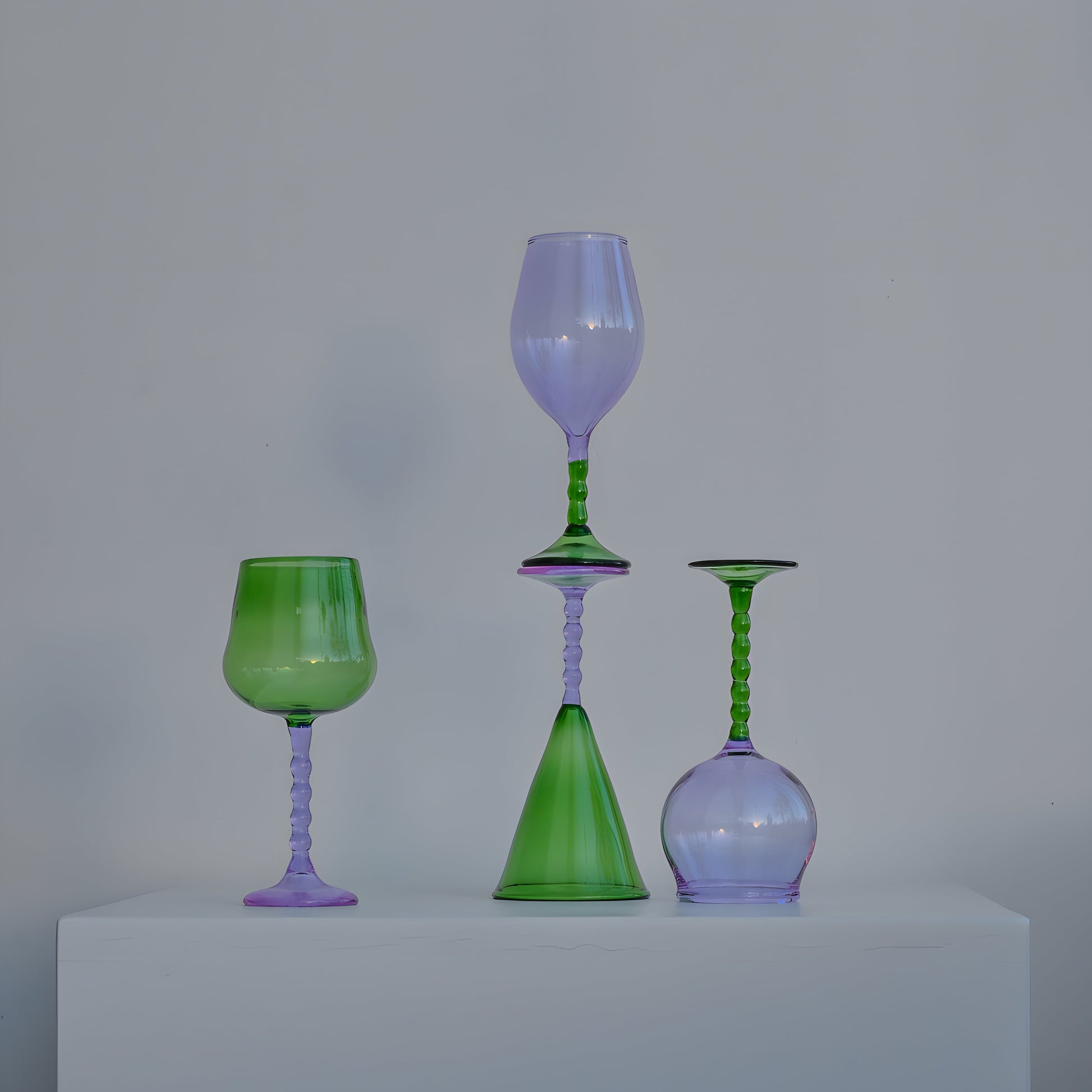 Handcrafted Teta Edit Liquor glasses set in green and lavender tones, artistically arranged on a white pedestal for a refined aesthetic.