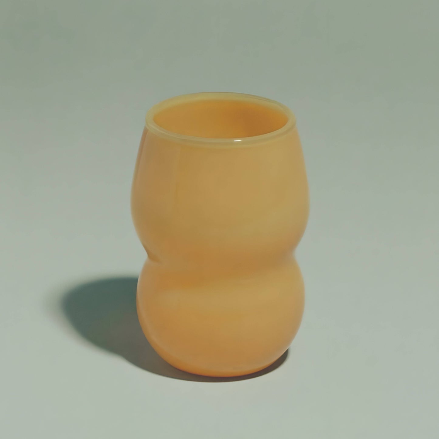 A handcrafted cup from the Dreamlike Collection, featuring whimsical curves and a vibrant interplay of color and light.