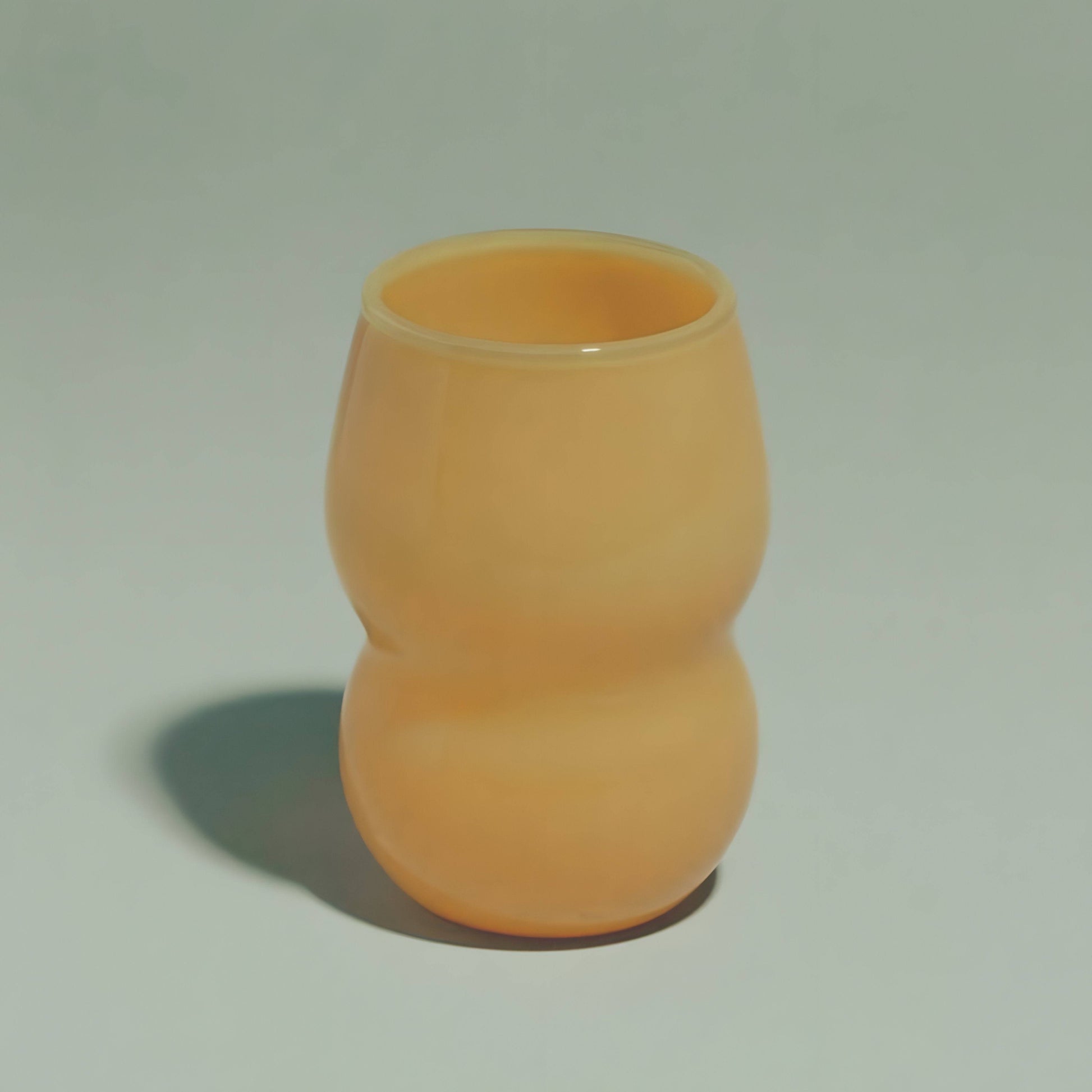 A handcrafted cup from the Dreamlike Collection, featuring whimsical curves and a vibrant interplay of color and light.