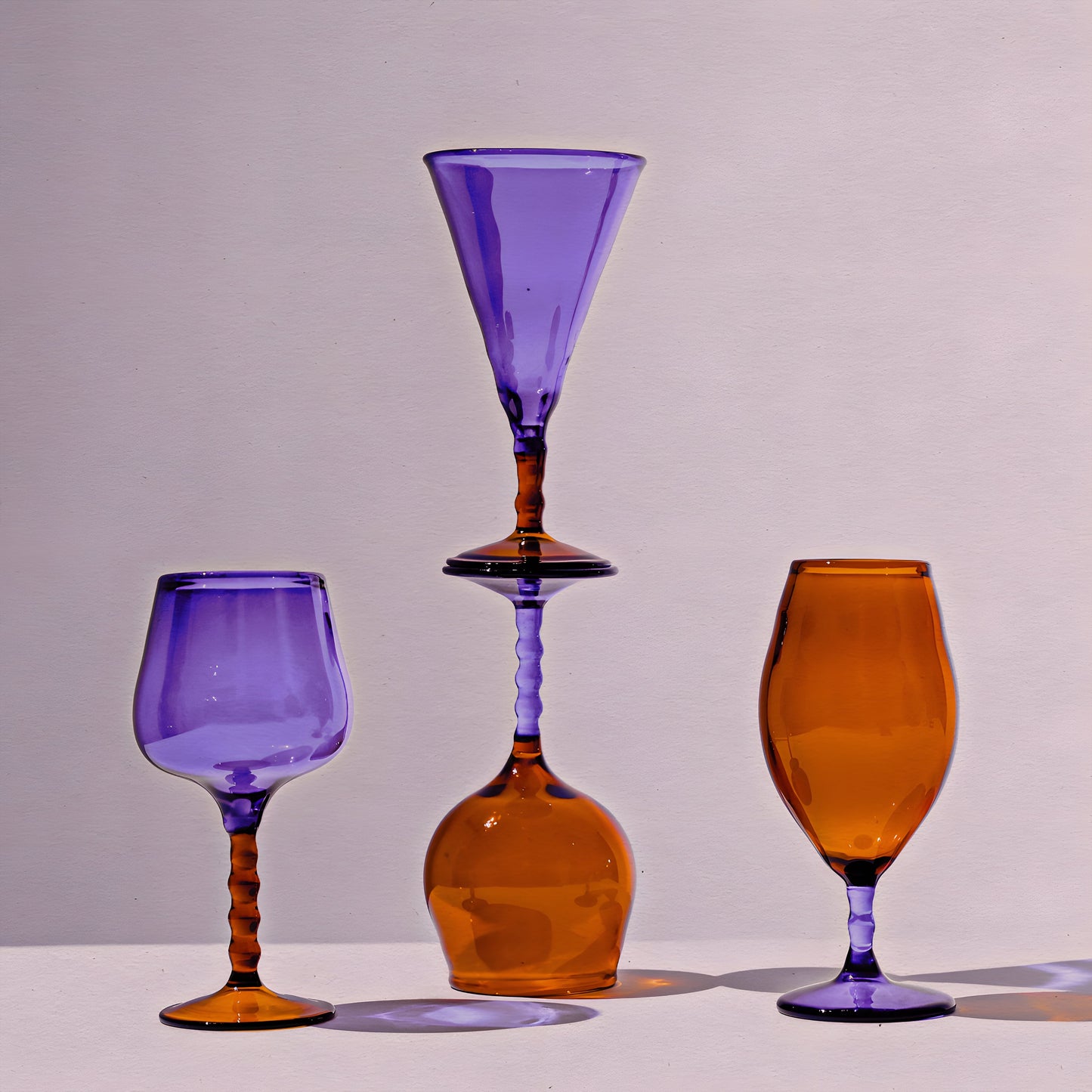 Teta Edit Liquor glasses set featuring handcrafted barware in amber and violet hues, elegantly stacked for a unique display.