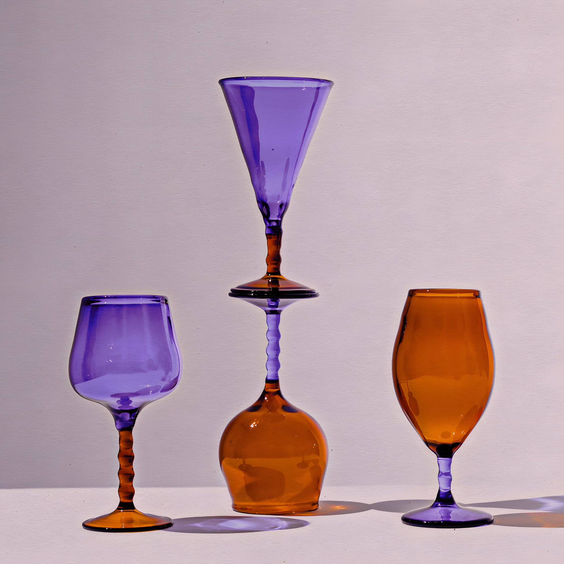 Teta Edit Liquor glasses set featuring handcrafted barware in amber and violet hues, elegantly stacked for a unique display.
