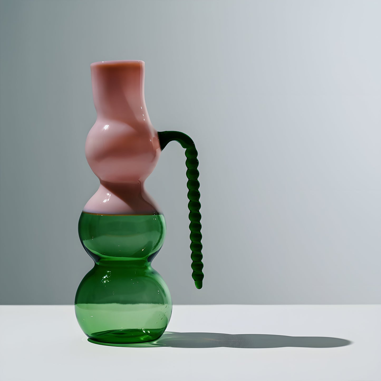 Dreamlike Pitcher:  A handcrafted glass pitcher with a whimsical silhouette, blending fluid curves and bold color contrasts. Mouth-blown by artisans, its ethereal form plays with transparency and light, adding an artful touch to any table setting.