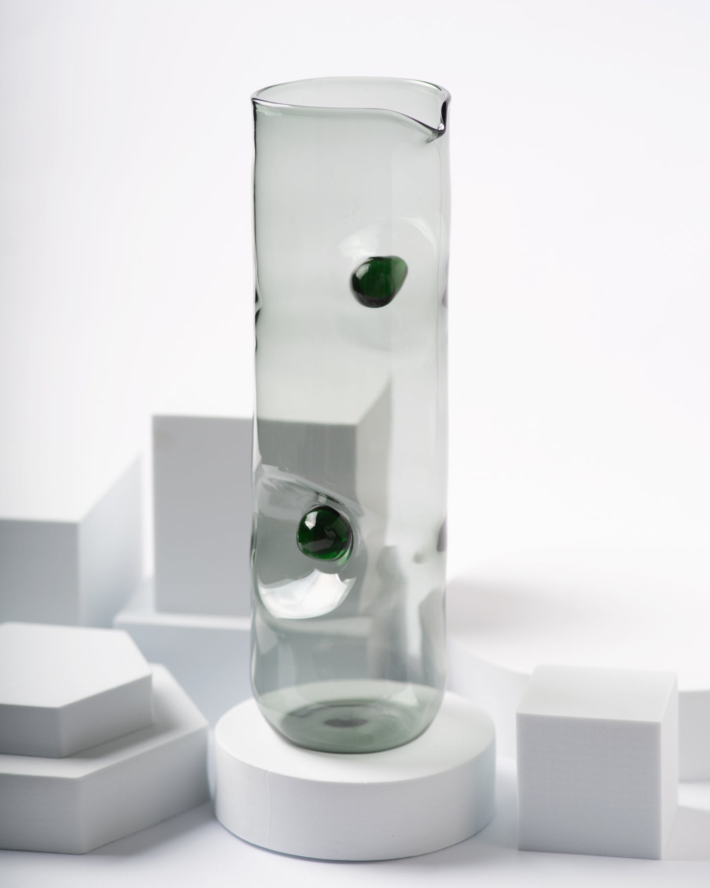Smoky gray glass pitcher from the Eye Candy collection by Ornamental by Lameice with deep green circular accents. A contemporary and artistic serveware piece for any occasion.